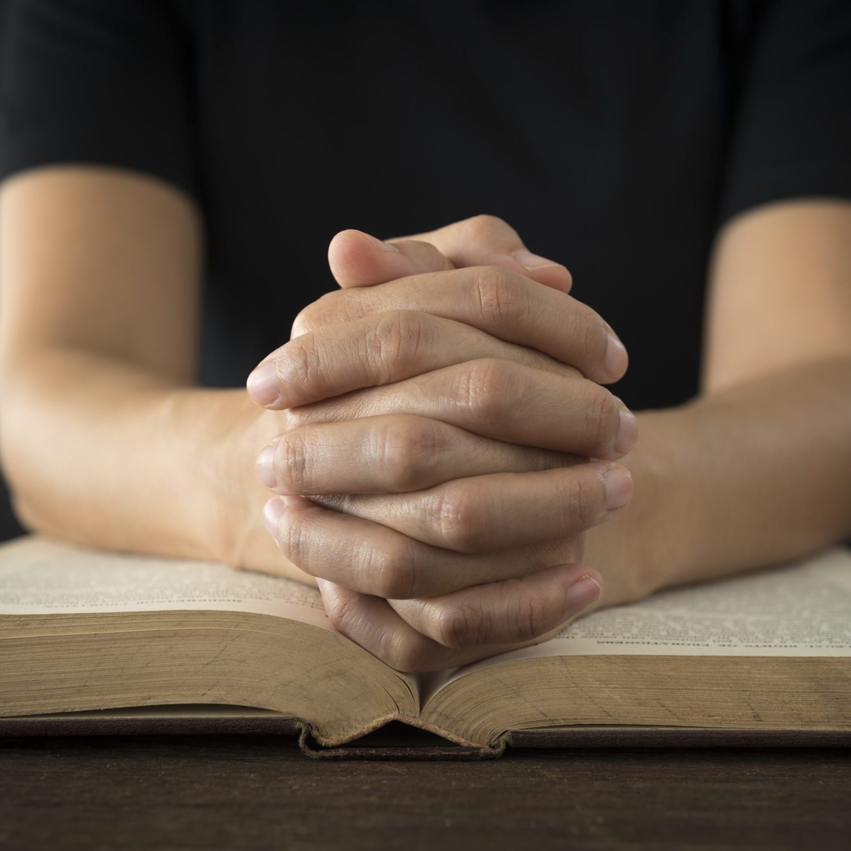 Hands of a human in prayer on a Holy Bible . religion concept.
